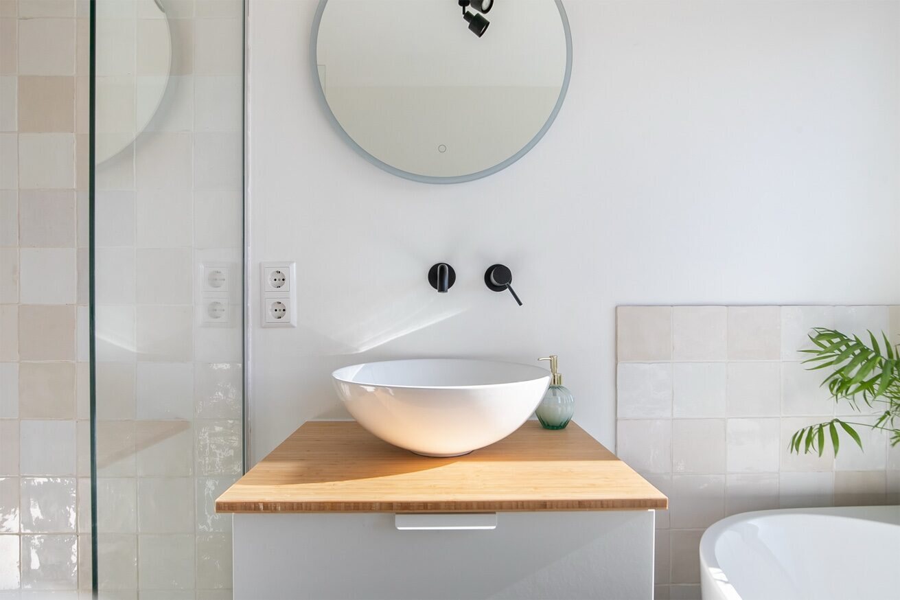 Wastafelmeubel met houten blad, ronde spiegel en handgemaakte witte tegels